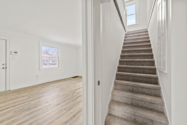 stairs with crown molding and wood-type flooring