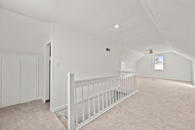 additional living space with vaulted ceiling, a textured ceiling, and light colored carpet