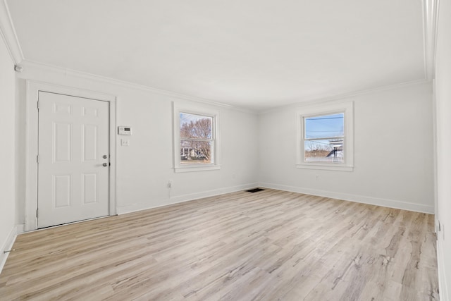 empty room with ornamental molding, plenty of natural light, and light hardwood / wood-style flooring