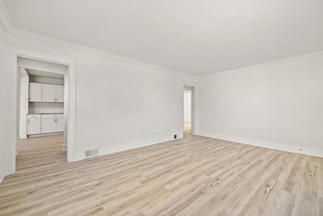 empty room with ornamental molding and light wood-type flooring