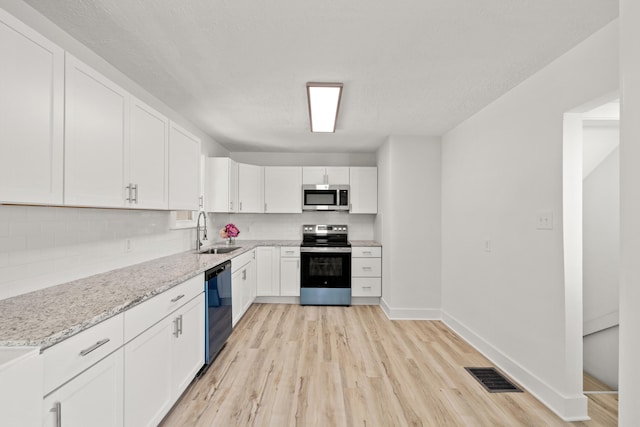 kitchen with sink, appliances with stainless steel finishes, white cabinets, and light stone counters