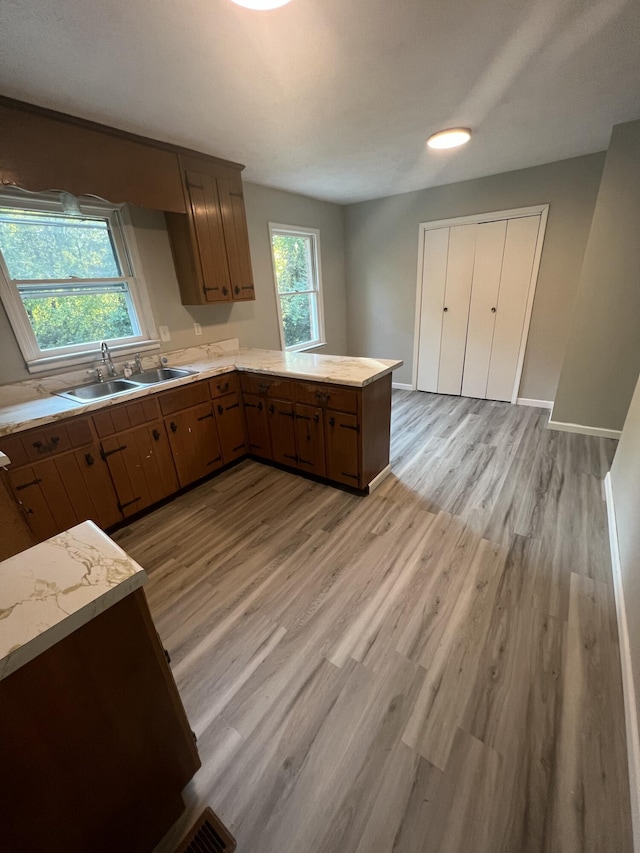 kitchen featuring sink, kitchen peninsula, and light hardwood / wood-style flooring