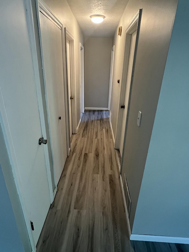 hallway with wood-type flooring and a textured ceiling