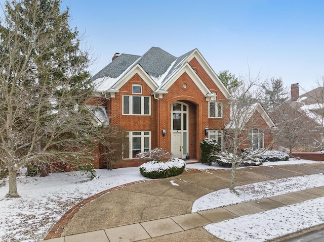 view of front of home with a chimney and brick siding