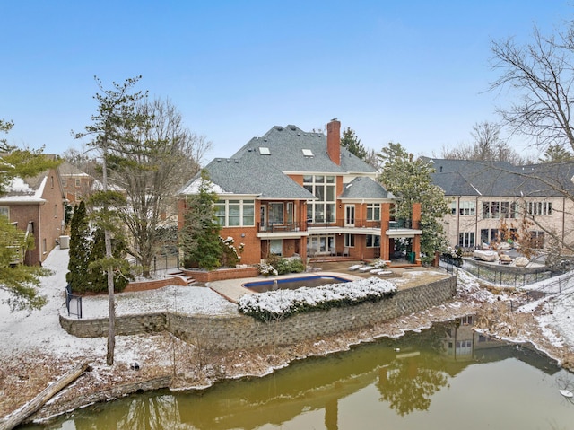 back of house featuring a chimney, a water view, and a residential view