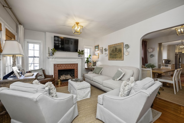 living room with wood-type flooring, a notable chandelier, and a fireplace