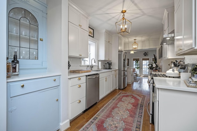 kitchen with appliances with stainless steel finishes, sink, pendant lighting, and white cabinetry