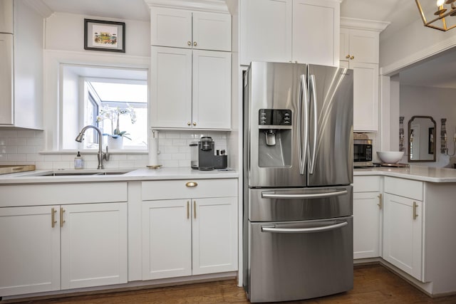 kitchen featuring sink, backsplash, white cabinets, and stainless steel refrigerator with ice dispenser