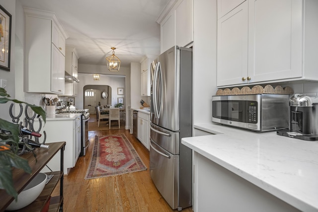 kitchen with appliances with stainless steel finishes, white cabinets, light stone countertops, and pendant lighting