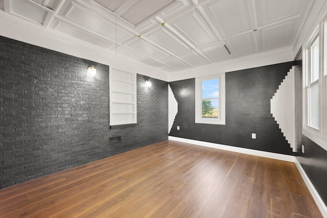 empty room with an ornate ceiling, hardwood / wood-style flooring, brick wall, and baseboards