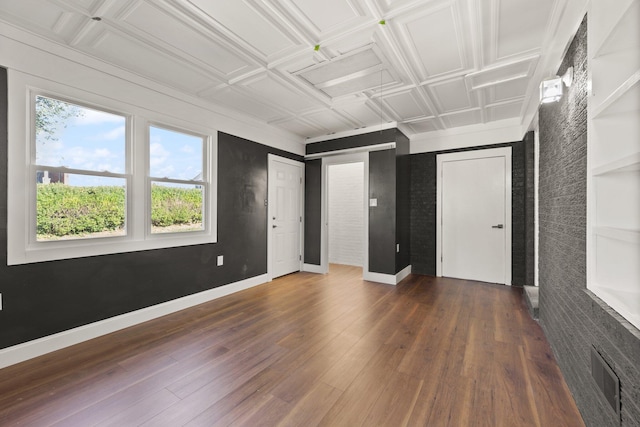 empty room featuring visible vents, wood finished floors, an ornate ceiling, and baseboards