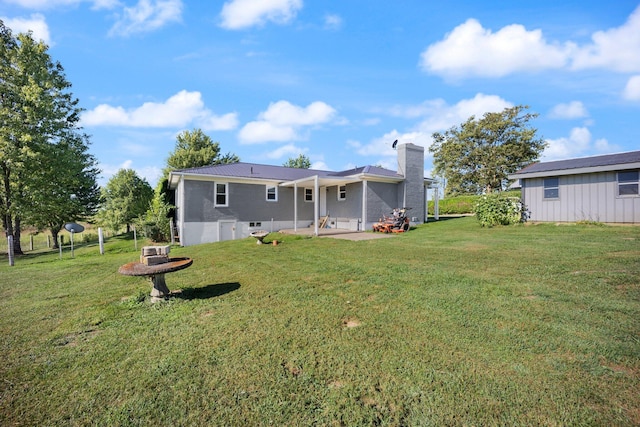 rear view of house with a patio, a lawn, and a chimney