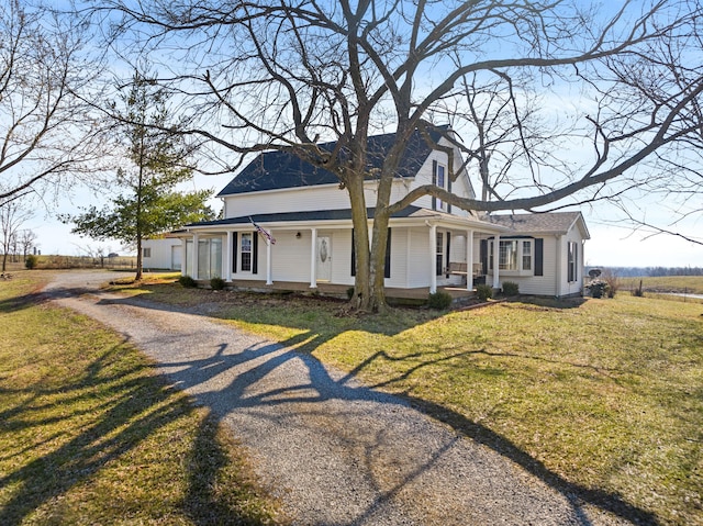 country-style home featuring a porch, a front yard, and gravel driveway