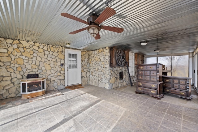 unfurnished living room featuring wood ceiling, a wood stove, and ceiling fan