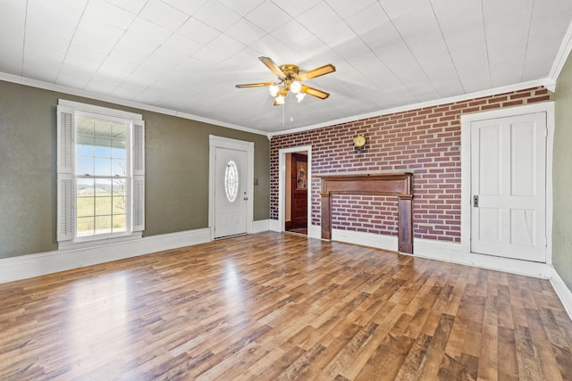 unfurnished living room with brick wall, wood finished floors, a ceiling fan, baseboards, and ornamental molding