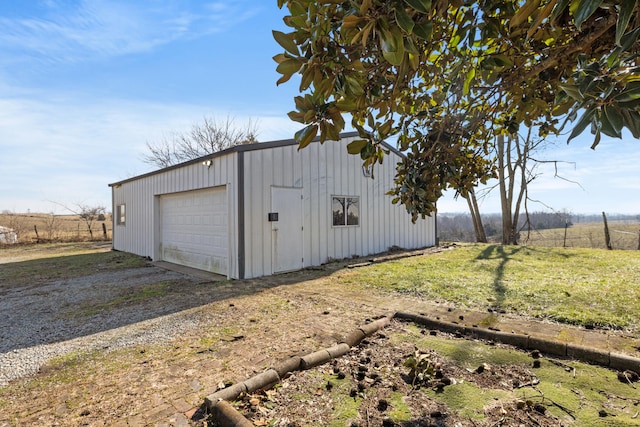 detached garage featuring a rural view and dirt driveway