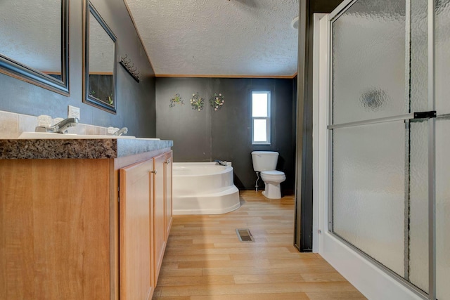 bathroom with a textured ceiling, wood finished floors, visible vents, a shower stall, and a bath