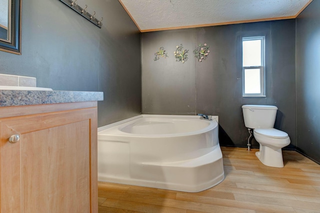 bathroom with a bath, toilet, wood finished floors, and vanity