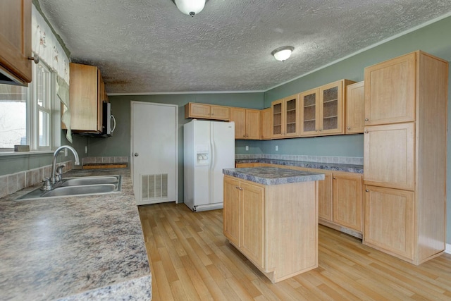 kitchen with a sink, visible vents, a kitchen island, white fridge with ice dispenser, and glass insert cabinets