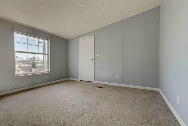 carpeted spare room featuring crown molding, visible vents, vaulted ceiling, a textured ceiling, and baseboards