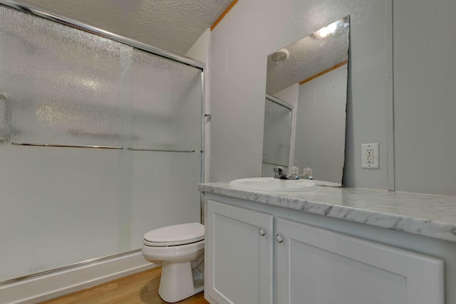 full bath with a stall shower, a textured ceiling, vanity, and wood finished floors