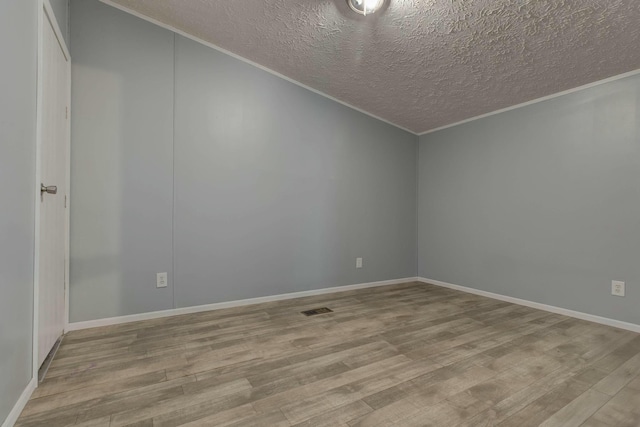 spare room with baseboards, visible vents, ornamental molding, a textured ceiling, and light wood-style floors