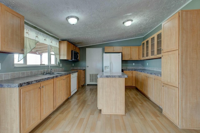 kitchen featuring a center island, dark countertops, visible vents, glass insert cabinets, and white appliances