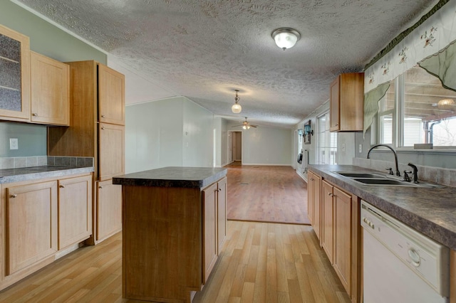 kitchen with dark countertops, glass insert cabinets, white dishwasher, a sink, and a kitchen island