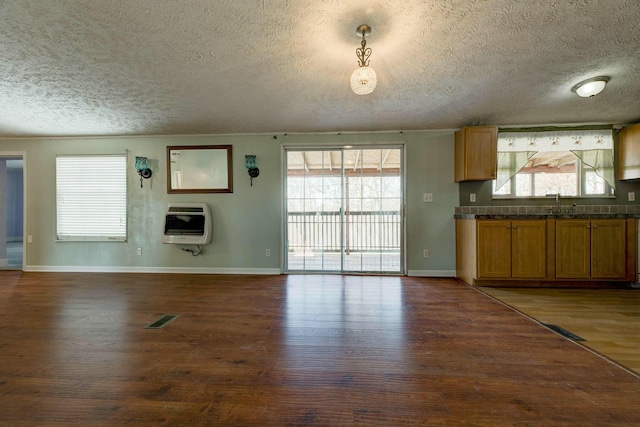 kitchen with dark wood-style flooring, visible vents, heating unit, dark countertops, and decorative light fixtures