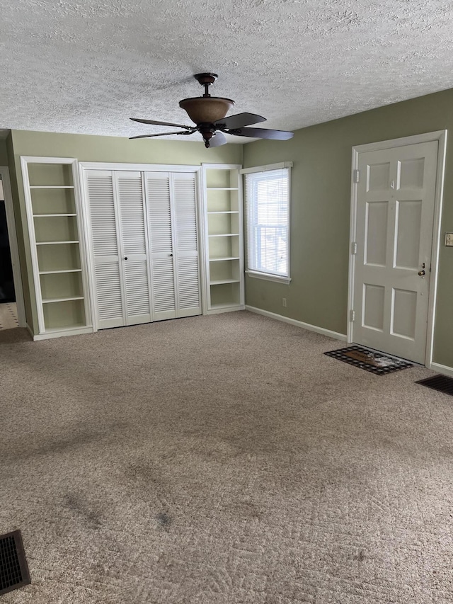 interior space with a textured ceiling, carpet floors, and baseboards