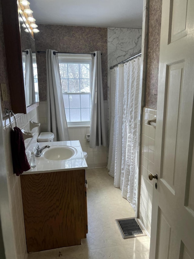 full bathroom featuring toilet, visible vents, tile walls, and vanity