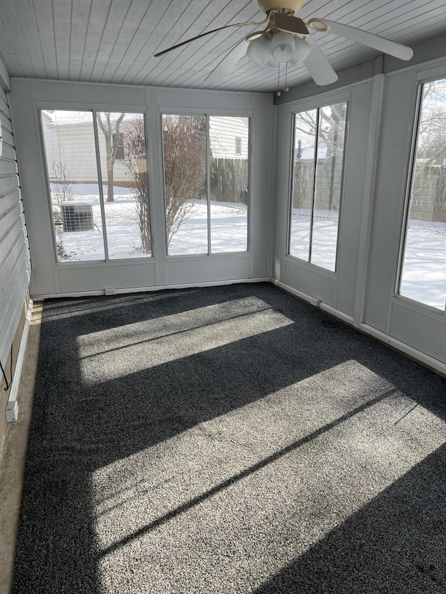 unfurnished sunroom with wooden ceiling, a ceiling fan, and a wealth of natural light