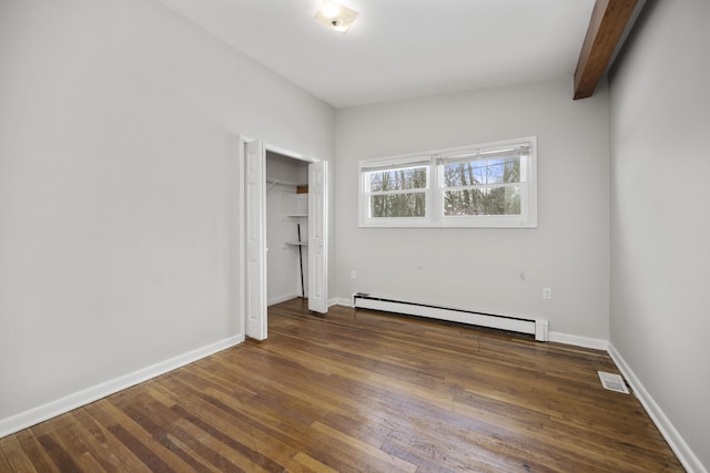 unfurnished bedroom with dark wood-style flooring, a closet, visible vents, baseboard heating, and baseboards