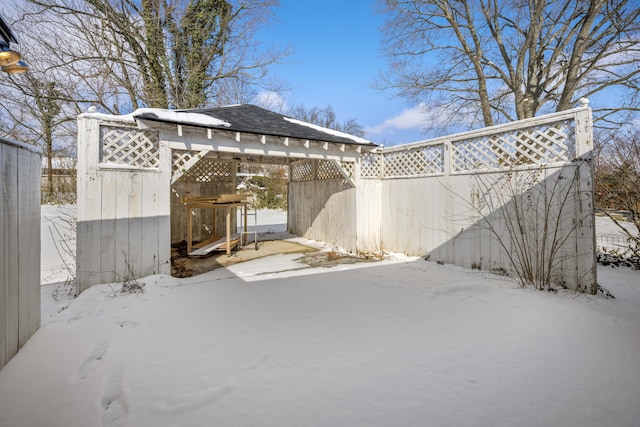 snow covered back of property featuring roof with shingles