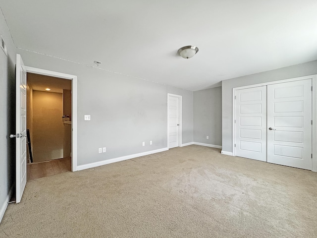 unfurnished bedroom with a closet, baseboards, and carpet flooring