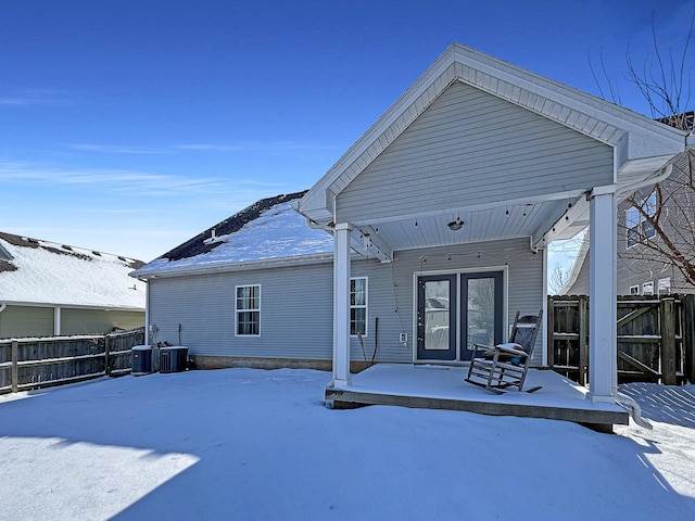 snow covered property with fence and central AC