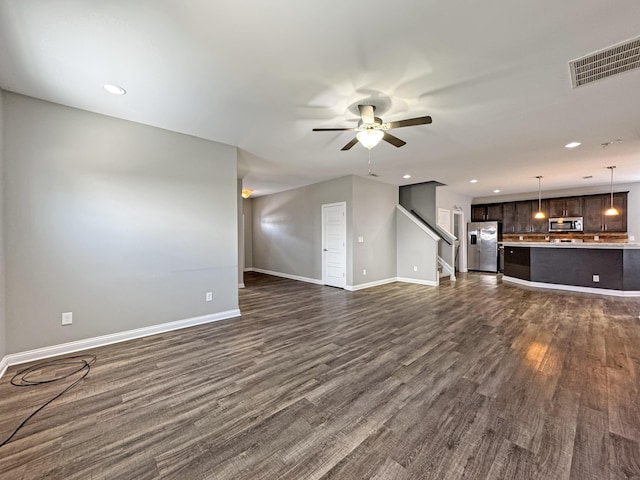 unfurnished living room with dark wood-style floors, visible vents, baseboards, and a ceiling fan