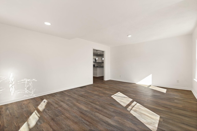 empty room featuring dark wood-type flooring, recessed lighting, and baseboards