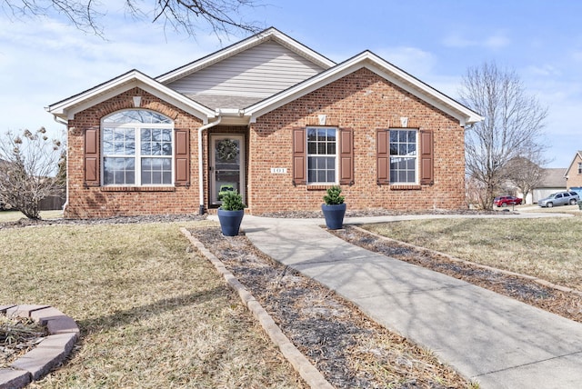 ranch-style home featuring roof with shingles, a front yard, and brick siding