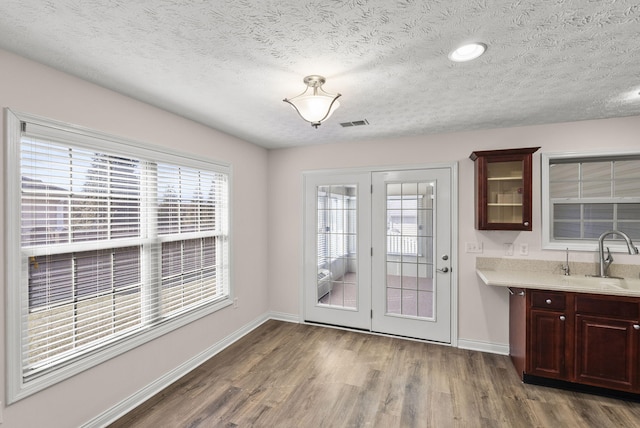 interior space featuring a textured ceiling, wood finished floors, a sink, and baseboards