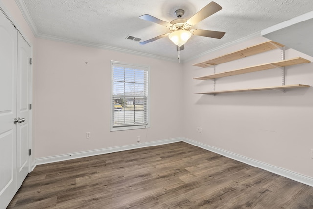 unfurnished bedroom featuring a textured ceiling, wood finished floors, visible vents, and crown molding