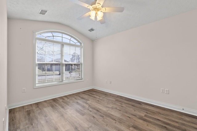 unfurnished room with baseboards, visible vents, wood finished floors, vaulted ceiling, and a textured ceiling