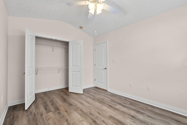 unfurnished bedroom with lofted ceiling, a closet, ceiling fan, wood finished floors, and baseboards