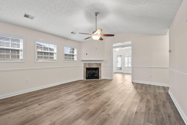 unfurnished living room with vaulted ceiling, a textured ceiling, a fireplace, and wood finished floors