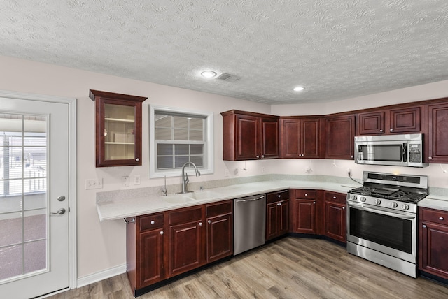 kitchen featuring dark brown cabinets, appliances with stainless steel finishes, light countertops, and a sink