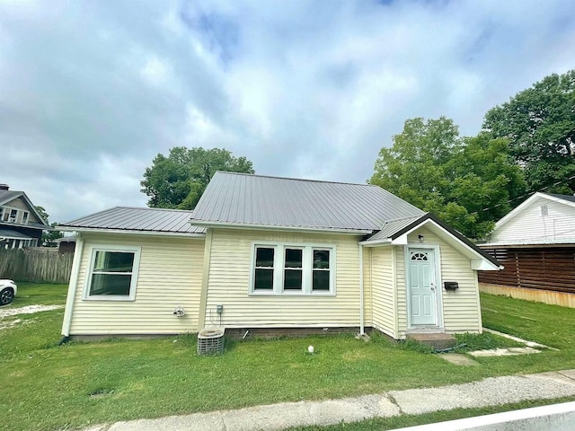 rear view of property with fence, metal roof, and a yard