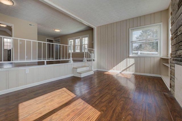 interior space featuring baseboards, visible vents, stairway, dark wood-type flooring, and a textured ceiling