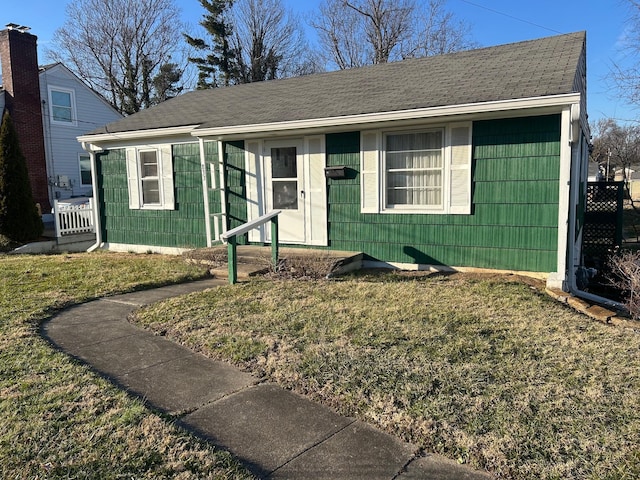 ranch-style home with a front lawn and roof with shingles