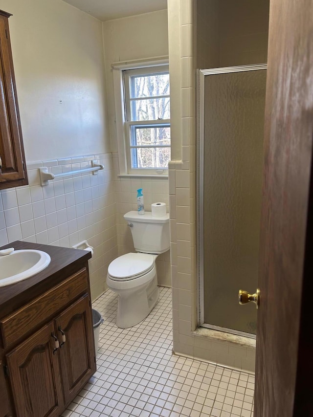 full bath with a stall shower, toilet, tile patterned floors, vanity, and tile walls