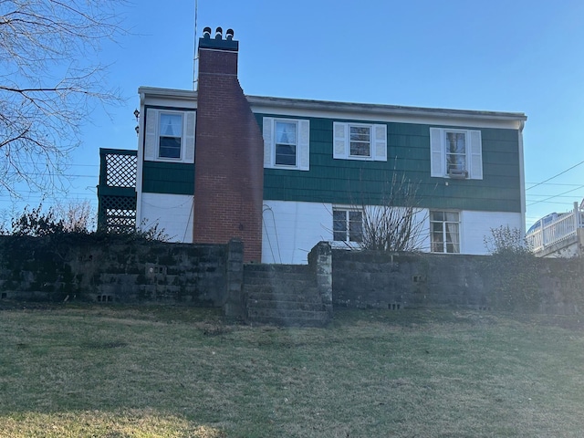 back of property with a chimney and a yard